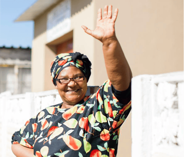 An older lady wearing glasses waving