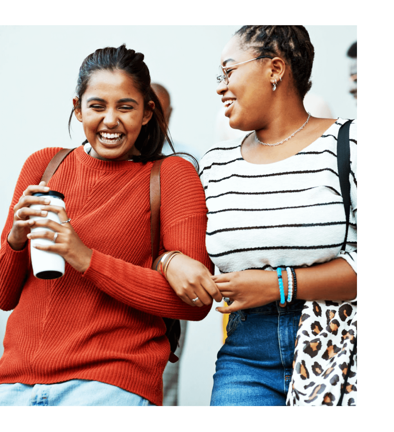 Two cheerful friends locking in arms and happily laughing
